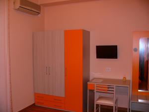 pomarańczowo-biała szafka w pokoju z biurkiem w obiekcie B&B Max w mieście Mesyna