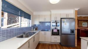a kitchen with white cabinets and a stainless steel refrigerator at Lonerock Unit 2 in Yamba
