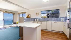 a kitchen with white cabinets and a view of the ocean at Lonerock Unit 2 in Yamba