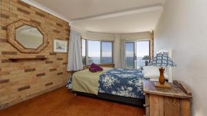 a bedroom with a bed and a mirror at Lonerock Unit 2 in Yamba +10 photos