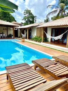 a house with a swimming pool in front of a house at Suites Taipe in Trancoso