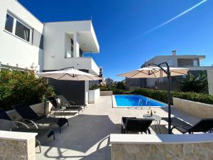 a patio with chairs and umbrellas next to a swimming pool at Fantasy Pool Villa in Novalja