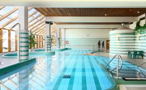 a swimming pool with blue tiles on the floor and ceilings at Spahotel Casino in Savonlinna