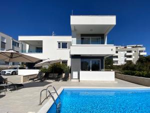 a house with a swimming pool in front of a building at Fantasy Pool Villa in Novalja