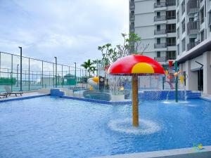 a pool with a umbrella in the middle of a building at Bali Sea View Residences Melaka at Stayrene in Melaka