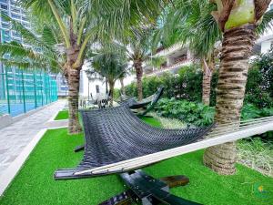 a hammock in a resort with palm trees at Bali Sea View Residences Melaka at Stayrene in Melaka