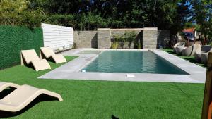a swimming pool with two chairs and some grass at Ak´Para in Tandil