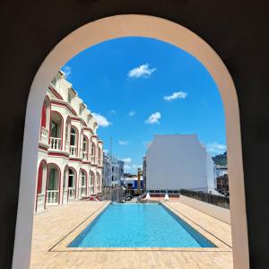 - une vue sur la piscine depuis une arche dans l'établissement Hotel Midtown Ratsada, à Phuket