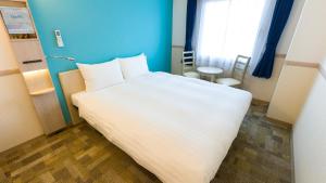 千葉市にある東横INN千葉幕張の青い壁の客室で、白い大型ベッド1台が備わります。