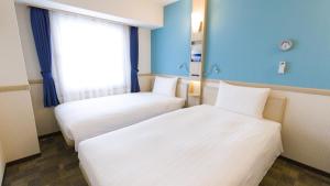Toyoko Inn Chiba Makuhari في شيبا: سريرين في غرفة بجدران زرقاء ونافذة