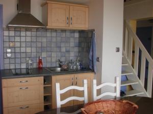 eine Küche mit Holzschränken, einem Waschbecken und einer Treppe in der Unterkunft IBIS in Saint Pierre La Mer