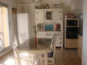 a kitchen with a glass table and a refrigerator at IBIS in Saint Pierre La Mer