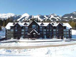 um grande edifício com montanhas cobertas de neve ao fundo em Fully Renovated Ski-in/out Loft with Private Hot Tub! em Golden