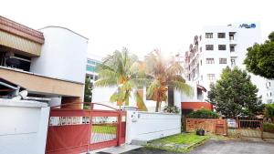 une porte rouge en face d'un bâtiment planté de palmiers dans l'établissement Advent Homestay, Penang - Near Adventist Hospital, à George Town