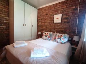 a bedroom with a white bed with a brick wall at Stone Circle Cottage in Lydenburg