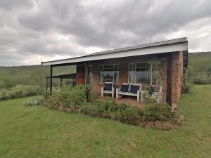 a brick house with two chairs in a yard at Stone Circle Cottage in Lydenburg