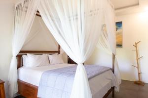 Schlafzimmer mit Himmelbett und weißen Vorhängen in der Unterkunft Variegata Private Villa Ubud by Supala in Ubud