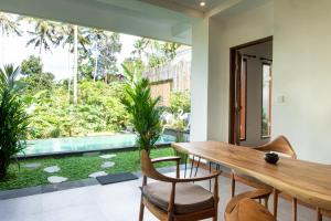 ein Esszimmer mit einem Holztisch und Stühlen in der Unterkunft Variegata Private Villa Ubud by Supala in Ubud