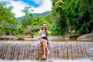 a woman sitting on top of a waterfall at Green Valley Veal Pouch in Kampot