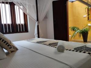 - une chambre avec un lit doté de draps blancs et d'une plante dans l'établissement Glamour Mirissa, à Mirissa