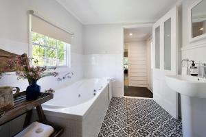 a white bathroom with a tub and a sink at Foxmere in Daylesford