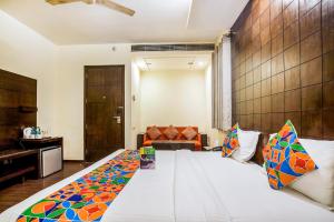 a bedroom with a large white bed with colorful pillows at FabHotel Aashraye in New Delhi