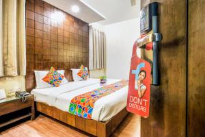 a hotel room with a bed with a sign that says dont disturb at FabHotel Aashraye in New Delhi