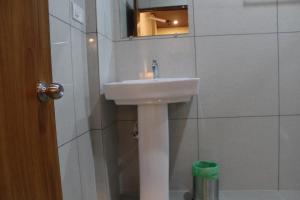 a bathroom with a white sink and a mirror at Vasathi in Madikeri