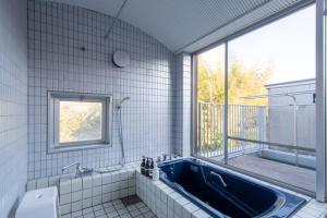 ein Bad mit einer blauen Badewanne und einem Fenster in der Unterkunft Shiki&Kura in Kurashiki