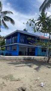 een blauw gebouw op het strand met een palmboom bij Azure at Tranquility Bay Beach Resort in Kinabutan