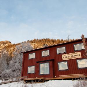 um edifício vermelho com um sinal na neve em Prästgården i Funäsdalen em Funäsdalen