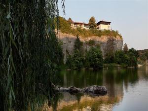 a house on a hill next to a body of water at Hotel Villa Kaylaka in Pleven