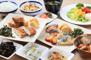 una mesa con platos de diferentes tipos de alimentos en Richmond Hotel Tenjin Nishi-Dori, en Fukuoka