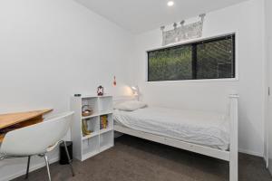 um quarto com uma cama, uma secretária e uma janela em Tapuaetahi Beach Marvel - Te Tii Holiday Home em Waipapa
