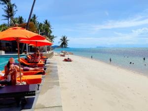 ein Strand mit Sonnenschirmen und Menschen am Strand in der Unterkunft Mimosa Resort & Spa in Mae Nam