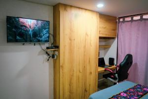 Habitación con tabique de madera y TV en la pared. en Acogedor loft frente al tranvía, en Medellín