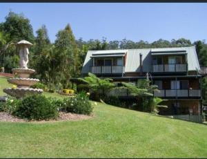 a house with a fountain in front of a yard at Spectacular Gold Coast Skyline Views in Mount Tamborine