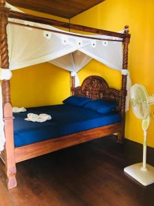 a bedroom with a canopy bed with blue sheets and a fan at Panorama Backpackers in Bunaken