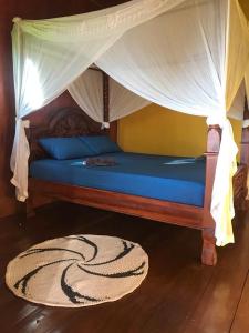 a bedroom with a bed with a canopy and a rug at Panorama Backpackers in Bunaken