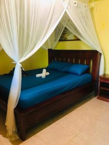 a bedroom with a blue bed with a canopy at Panorama Backpackers in Bunaken