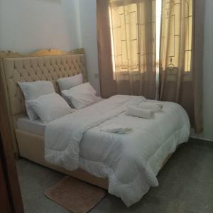 a large white bed with white sheets and pillows at PEARL LULU MODERN BNB Homestay in Dar es Salaam