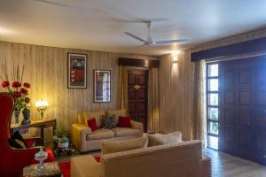 una sala de estar con un sofá y una silla en StayVista at Meraki Homestay - 2BR Pet Friendly Villa in Dharamshala, en Dharamshala
