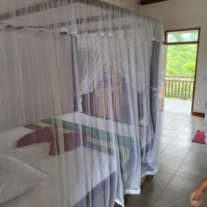 1 dormitorio con 1 cama con cortina blanca en Beach House Habaraduwa, en Koggala