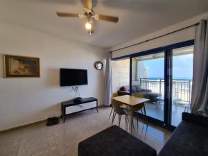 ein Wohnzimmer mit einem TV und einem Tisch mit Stühlen in der Unterkunft Sunset and sea view, wifi and more in Aschkelon