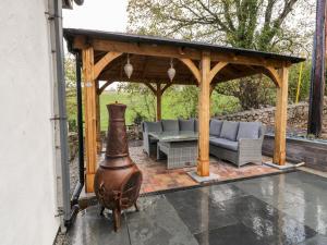 a wooden gazebo with a couch and chairs on a patio at Bryn Goleu in Llandudno