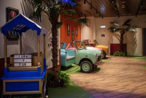 two old cars parked in a room with palm trees at Roaders Plus Hotel - Taipei Station in Taipei