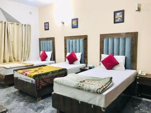 Pokój z 3 łóżkami i czerwonymi poduszkami w obiekcie HOTEL ROSE INN w mieście Lahaur