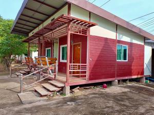 een rood huis met een veranda en stoelen bij โรงเกลือรีสอร์ท in Aranyaprathet