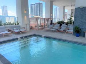 a swimming pool in a hotel with chairs and tables at Modern 1 Bed Condo across from Bayside in Downtown in Miami