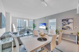 Modern 1 Bed ICON Brickell with Amazing Views في ميامي: غرفة طعام وغرفة معيشة مع طاولة وكراسي بيضاء